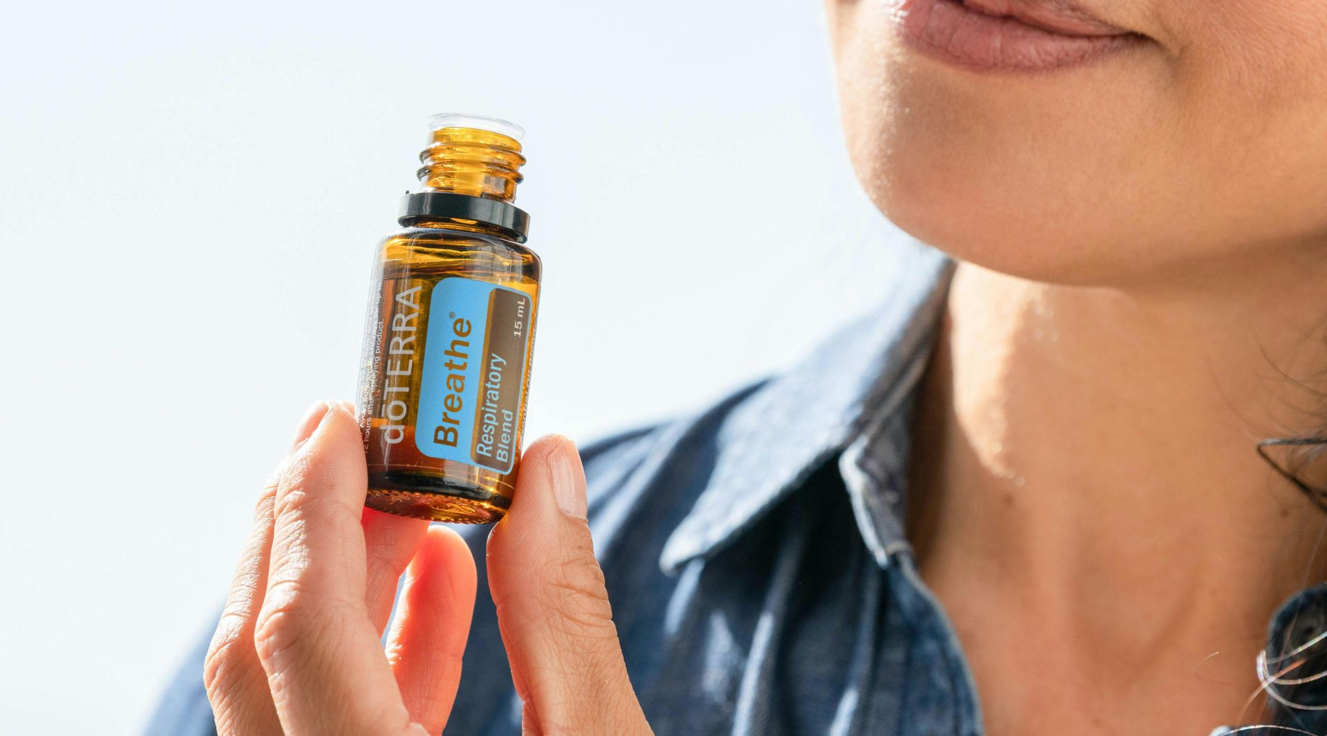 Woman in Blue Denim Jacket Holding Yellow Glass Bottle